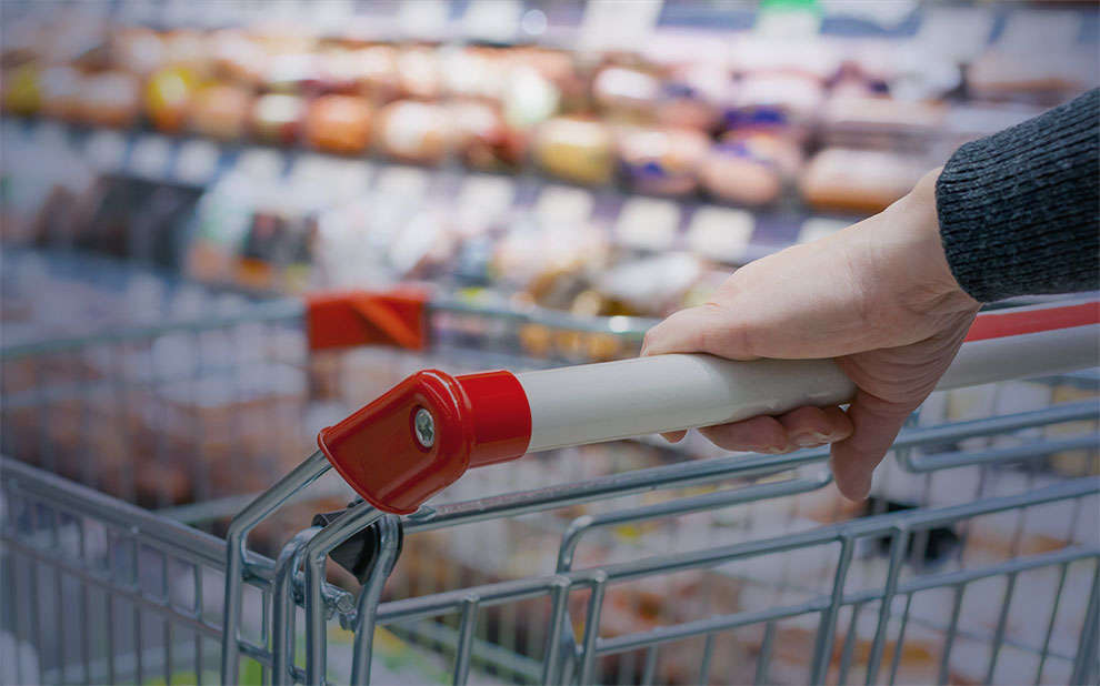 Pessoa empurra carrinho de mão em supermercado