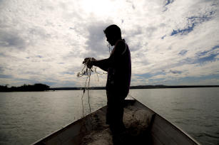 Pescador com rede na mão a foto está contra a luz